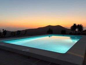 A rectangular swimming pool with a clear blue water surface, surrounded by a tiled deck. - Villa in Arenas with Sea Views and Private Pool (Arenas)