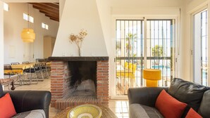 A living room with a fireplace, two sofas, a dining area, and a view of a pool. - Villa in Arenas with Sea Views and Private Pool (Arenas)