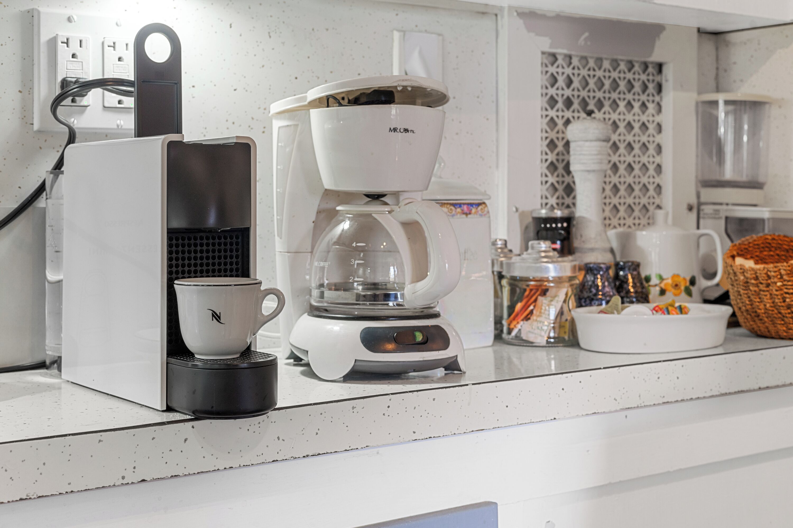 A coffee maker with a cup and a scale, a basket, and a decorative wall.