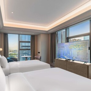 A hotel room with two beds, a TV on a stand, a small table, and a chair.