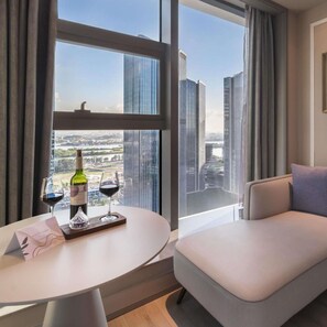 A modern hotel room with a dining area, a sofa, and a large window offering a city view. - Mercure Guangzhou Financial City (Guangzhou)