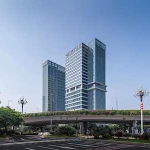 A modern high-rise building with a glass facade, located in an urban setting with a clear sky.