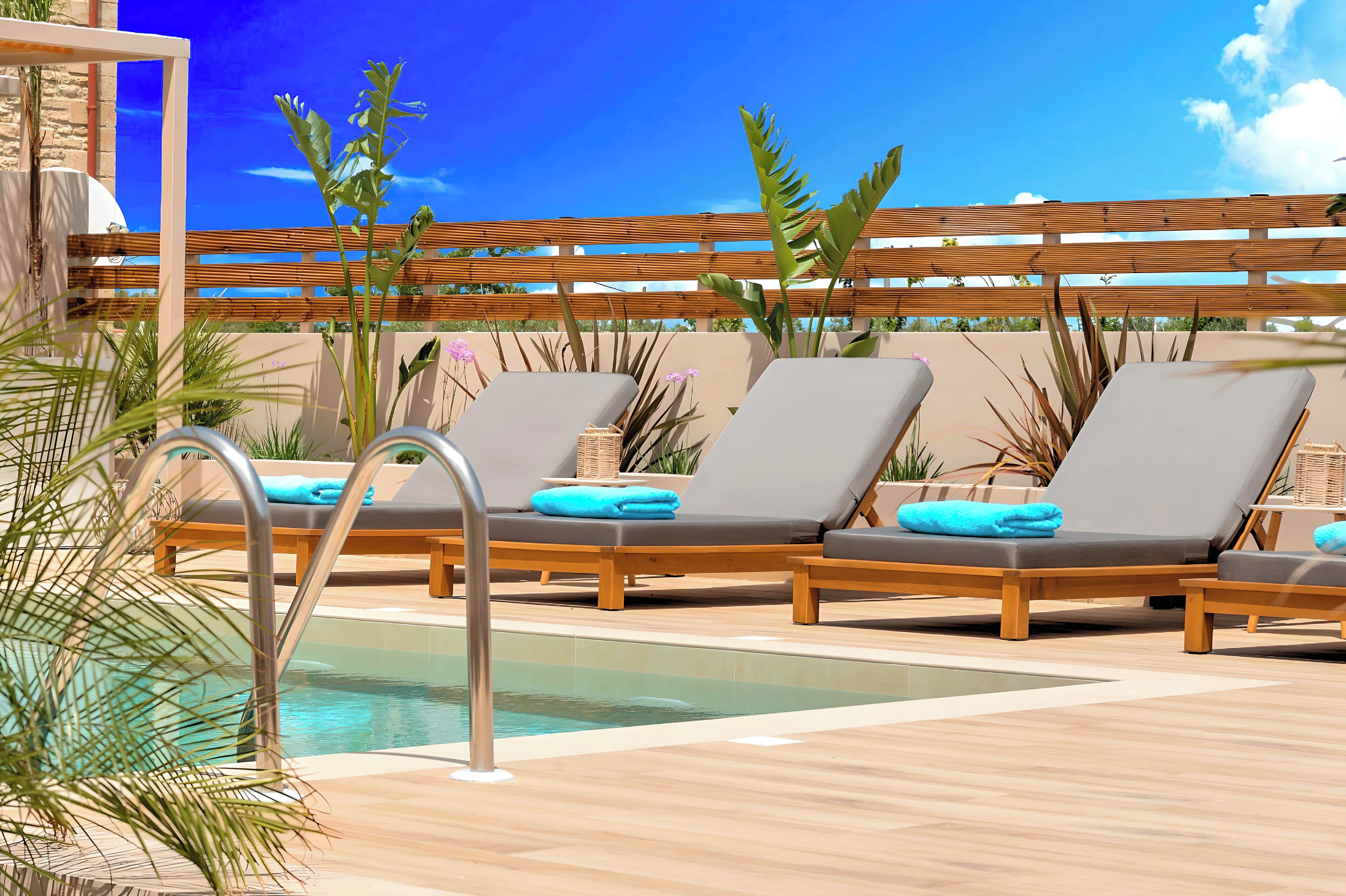 Un área junto a la piscina con sillones de descanso, piscina y una pérgola de madera.