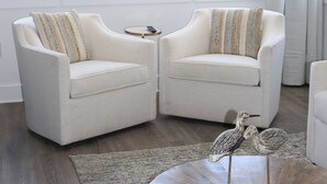 A living room with two white armchairs, a round wooden coffee table with bird sculptures, and a small round table with a remote control. - Treasure Cay, Palm Bay 7, Anchorage Drive (Treasure Cay)