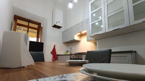 Une cuisine moderne avec des meubles blancs, une cuisinière et un coin repas comprenant une table et des chaises en bois.