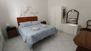 Une chambre à coucher comprenant un lit, des tables de chevet, une commode, un miroir et une décoration murale à motifs floraux.
