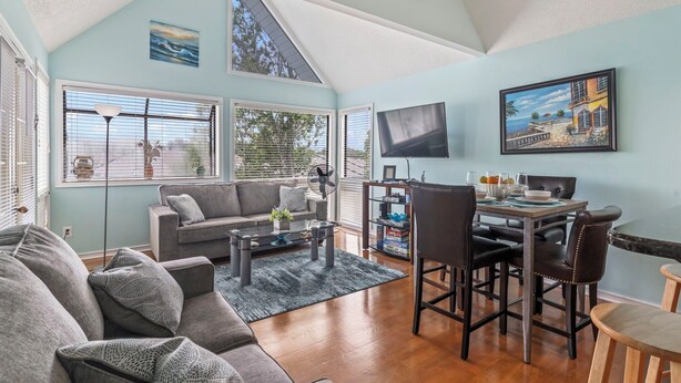 A spacious living room with a high ceiling, a dining area, and large windows. - Beach Life, Heated Pool, Hot Tub, Close to Beach (Myrtle Beach)