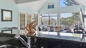 A modern kitchen with a granite countertop, a large island, and a dining area with a sofa and table. - Beach Life, Heated Pool, Hot Tub, Close to Beach (Myrtle Beach)