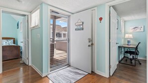 A room with a door leading to a balcony, a bed, a desk with a chair, and a lamp. - Beach Life, Heated Pool, Hot Tub, Close to Beach (Myrtle Beach)