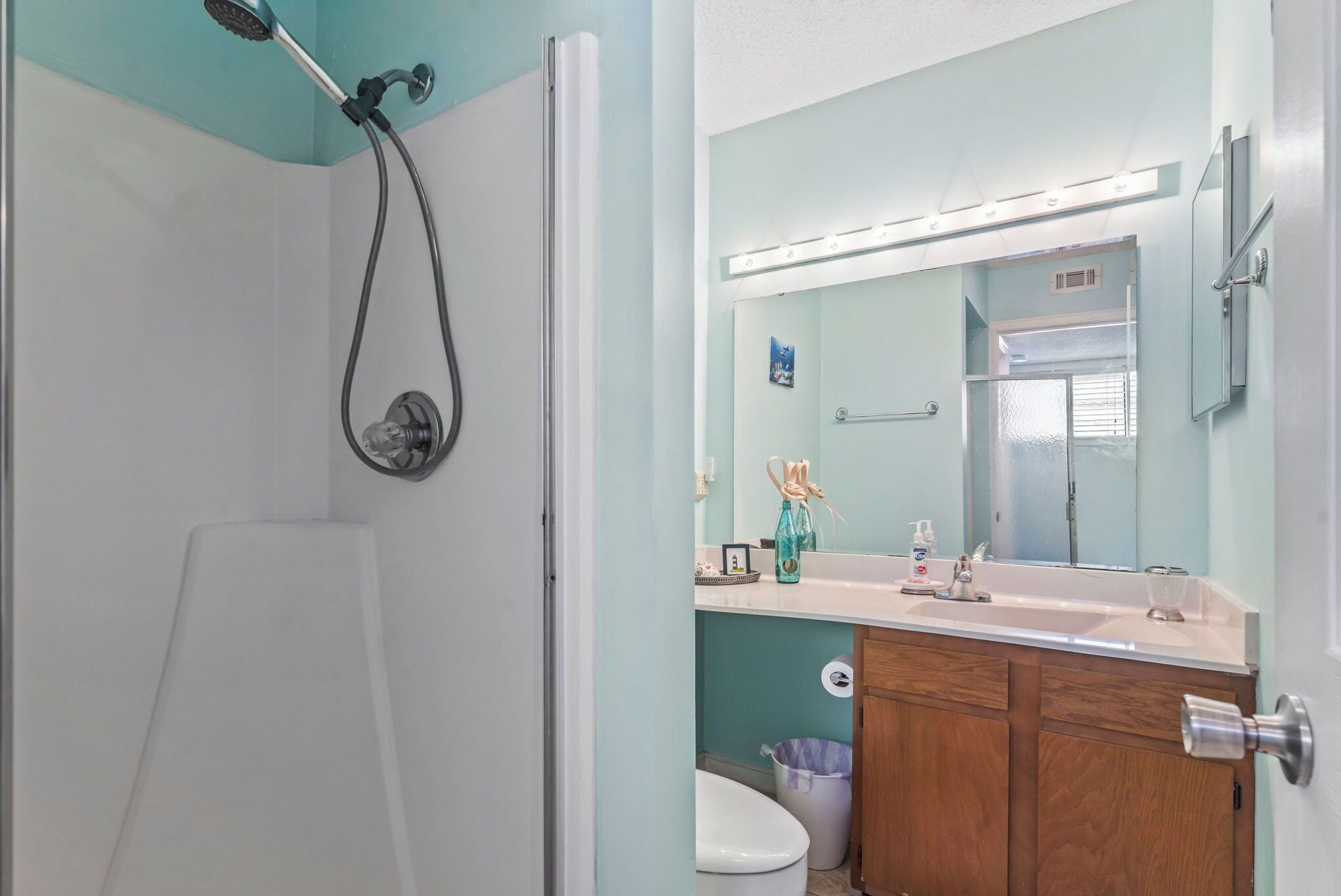 A bathroom with a shower, toilet, and vanity with a mirror.