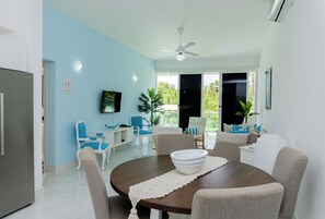 Enjoy meals in this dining area with a round table for four, a flat-screen TV, and a large window offering a view of the surrounding greenery.