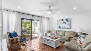 A living room with a ceiling fan, a white coffee table, a beige sofa, and a wicker rocking chair. - Your Perfect Vacation Townhome Just Steps from the Sand! - Full Amenities (Fort Pierce)