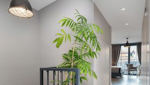 Un interior moderno con una escalera, una planta en maceta y vistas a otra habitación.