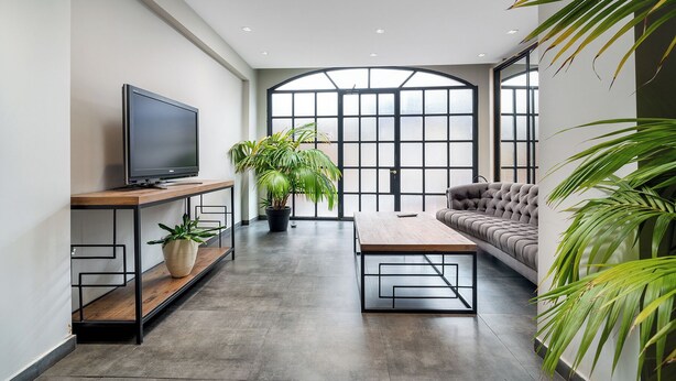 Una sala de estar moderna con un televisor de pantalla plana, un sofá, una mesa de centro y plantas en macetas.