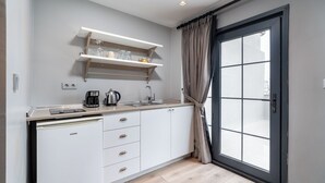 Una cocina moderna con armarios blancos, cafetera integrada y una ventana con cortinas.