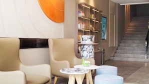 A modern lobby with seating, a staircase, and a wall-mounted shelf with items. - Homeinn · neo (Zhengzhou Hanghai Road Chengdong Nanlu Subway Station) (Zhengzhou)