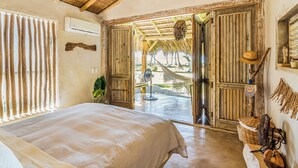 A room with a bed, a fan, and a view of the outside. - Casa Taina- 5 Bungalows, swimming pool- OCEANFRONT w/Butler and Chef (Cabrera María Trinidad)
