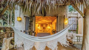 A hammock in a rustic room with a bed, wooden walls, and a thatched roof. - Casa Taina- 5 Bungalows, swimming pool- OCEANFRONT w/Butler and Chef (Cabrera María Trinidad)