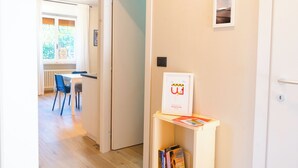 A hallway with a dining area, a door with a sign, and a small shelf with books. - Lemon Apartment with Garden and Sea View (Bordighera)