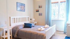 A bedroom with a bed, bedside tables, a lamp, and a window with curtains. - Lemon Apartment with Garden and Sea View (Bordighera)