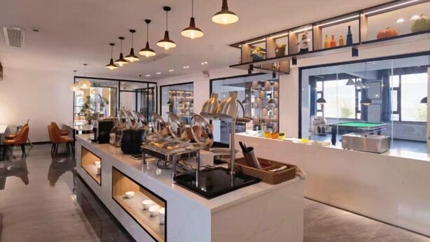 Un espace bar moderne doté d’un éclairage suspendu, d’une table de billard et d’un coin salon avec des chaises.