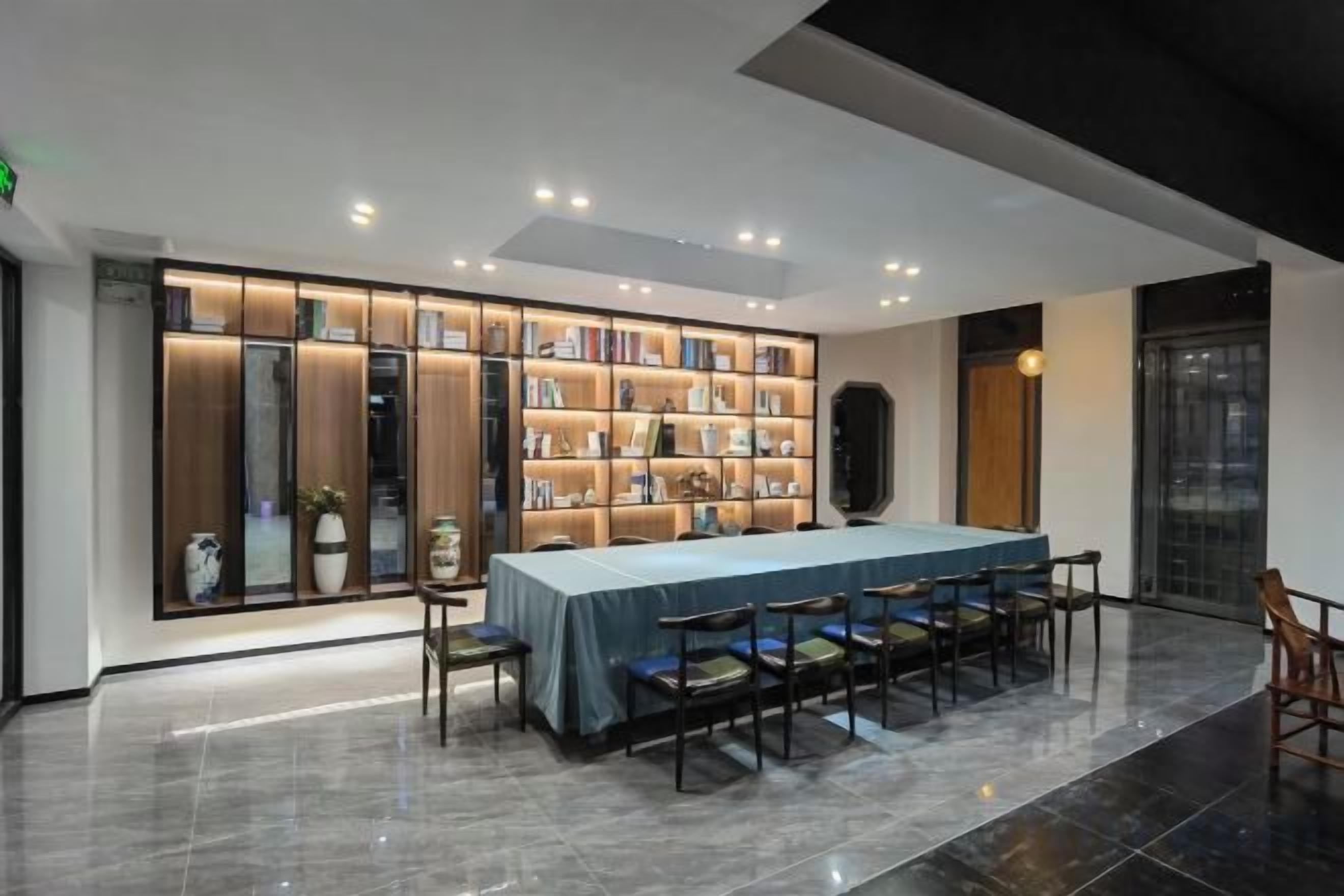 Una biblioteca moderna con una mesa grande y sillas, rodeada de estanterías.