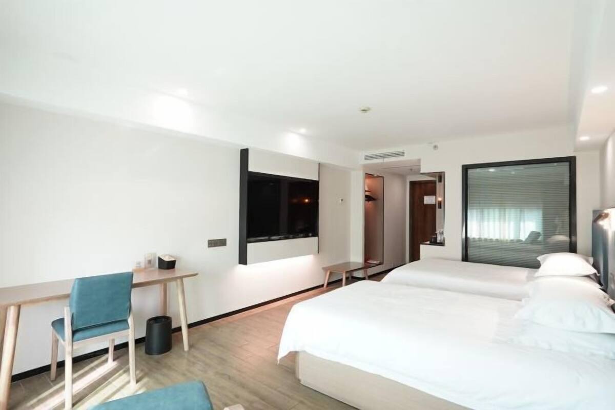 A modern hotel room with a bed, a desk, and a chair.