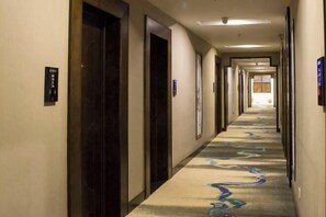 A hotel hallway with carpeted floors, doors, and a ceiling light. - Jinglan Yipin Hotel (Jingdezhen Taoxichuan Branch) (Jingdezhen)