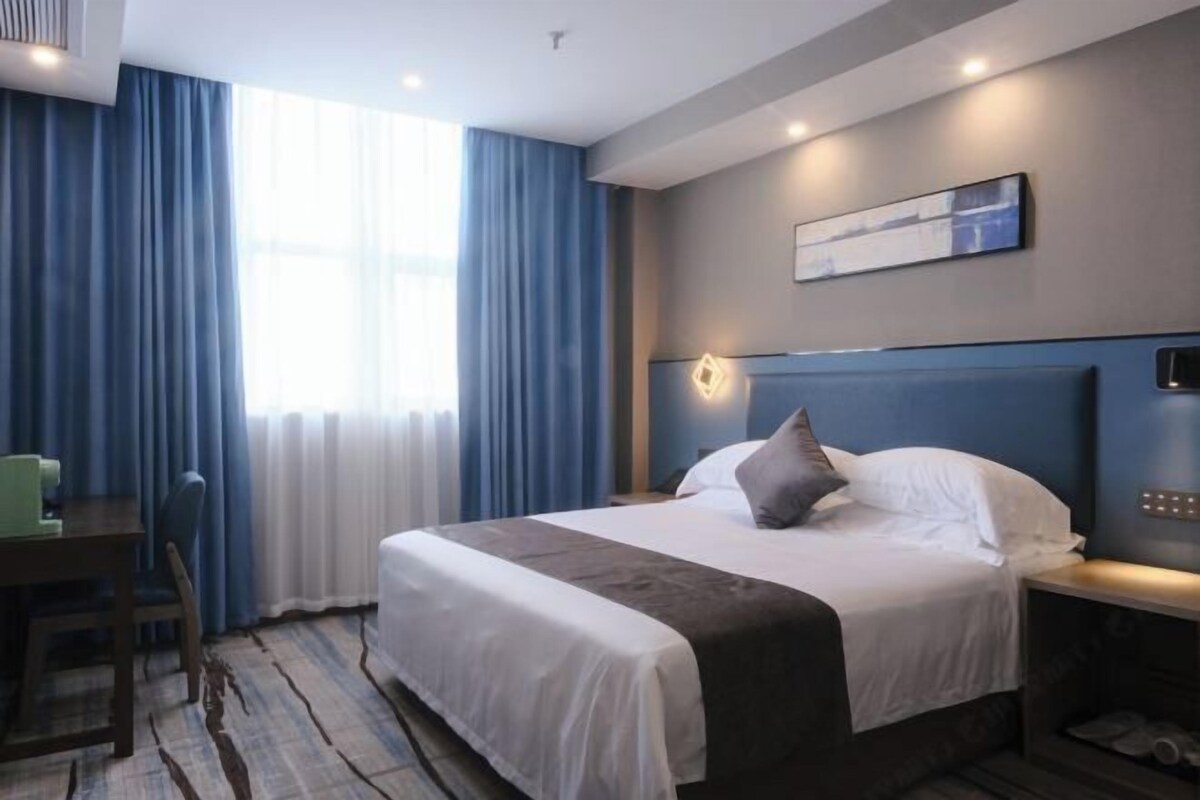 A hotel room with a bed, a desk, and a chair.