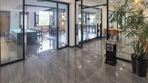 Un hall d’hôtel moderne avec des portes vitrées donnant accès à un espace de restauration.