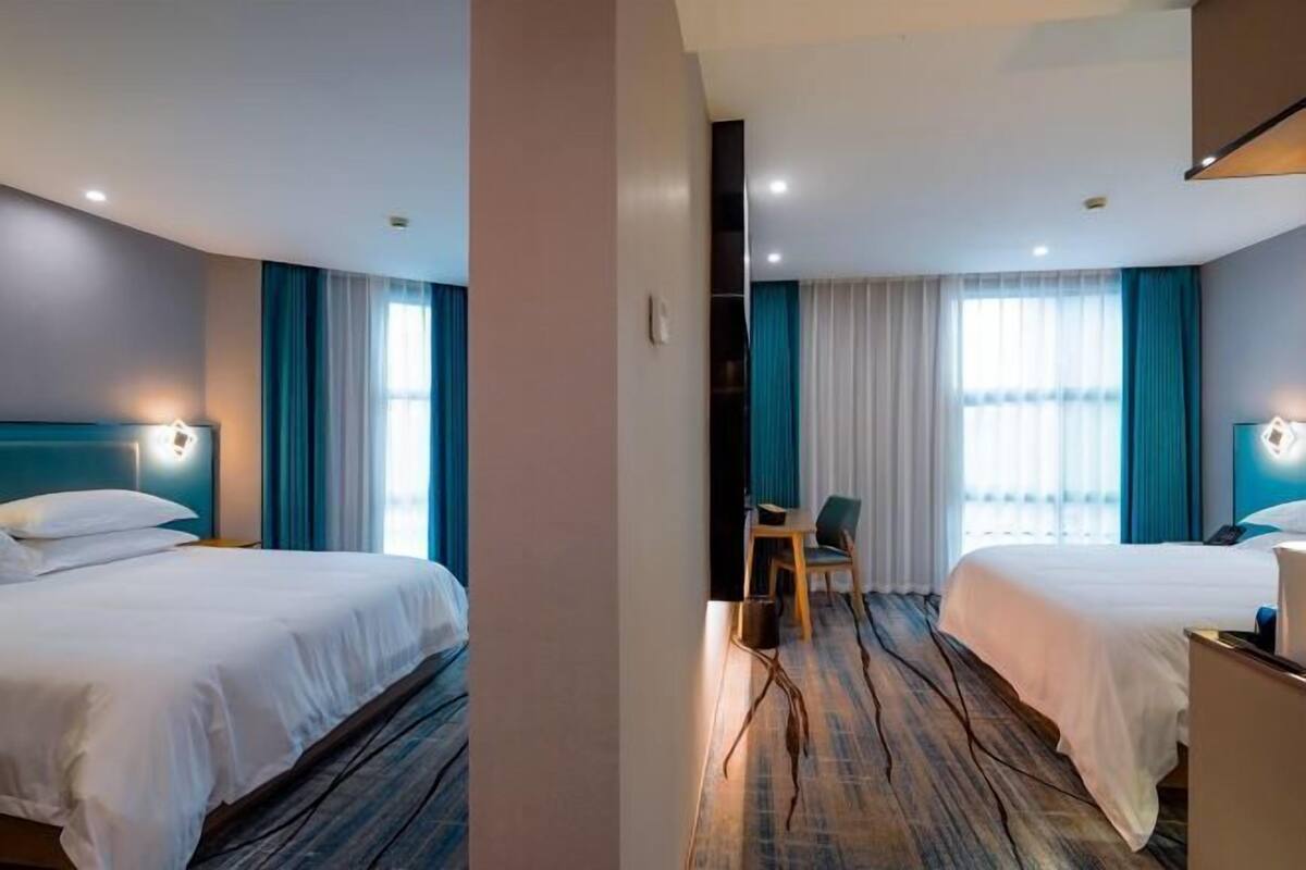 A hotel room with two beds, a desk, and a chair.