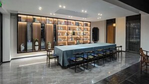 Une salle de conférence moderne, dotée d’une longue table, de chaises et d’une bibliothèque remplie de livres et d’objets décoratifs.