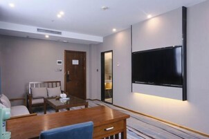 A modern living room with a wooden coffee table, a sofa, and a flat-screen TV mounted on the wall.
