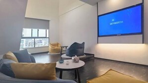 Un salon moderne comprenant un canapé, des fauteuils, une table basse et un grand écran affichant la marque « SKYWORTH ».