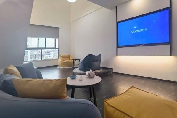 A modern living room with a sofa, armchairs, a coffee table, and a large screen displaying "SKYWORTH". - Jinglan Yipin Hotel (Jingdezhen Taoxichuan Branch) (Jingdezhen)