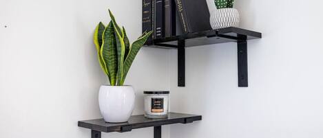 A black metal shelf with a potted plant, a white vase, and a candle.