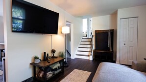 A bedroom with a bed, a TV mounted on the wall, a staircase, and a closet. - The Cooper Home, Dogs Welcome! (Ephrata)