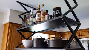 A kitchen with a black metal shelf holding various bottles and a can. - The Cooper Home, Dogs Welcome! (Ephrata)