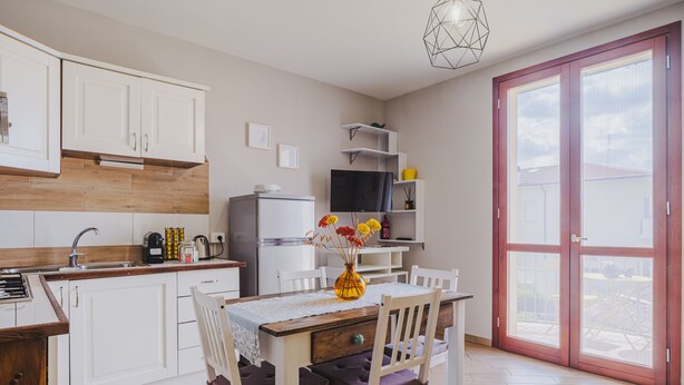 Une cuisine moderne avec des meubles blancs, un plan de travail en bois et un coin repas comprenant une table et des chaises.