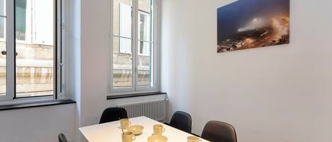 Une salle de conférence avec une table blanche, six chaises et un tableau représentant un paysage urbain.
