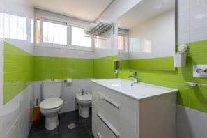 Features a toilet, bidet, and vanity with sink and mirror.