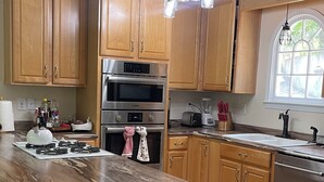 A kitchen with wooden cabinets, a large island, stainless steel appliances, and pendant lighting. - River tunes at its best panoramic views just steps away from the river  (Ellijay)