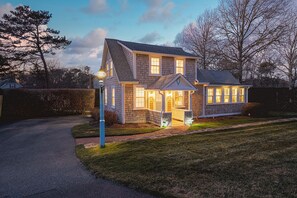 A two-story house with a front porch and a driveway leading to the entrance. - Beach Bungalow: Steps to Beach, Luxury Family Fun (Harwich)