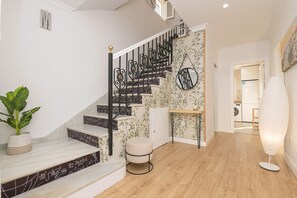 Staircase with a decorative railing and floral wallpaper, featuring a door to another room and a potted plant.