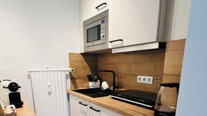 Et kompakt køkken med mikrobølgeovn, komfur og vask.