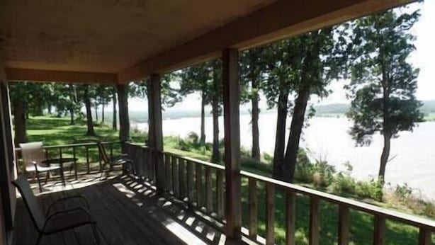 Eine Holterrasse mit Geländer, die auf einen See blickt, mit einem Tisch und zwei Stühlen.