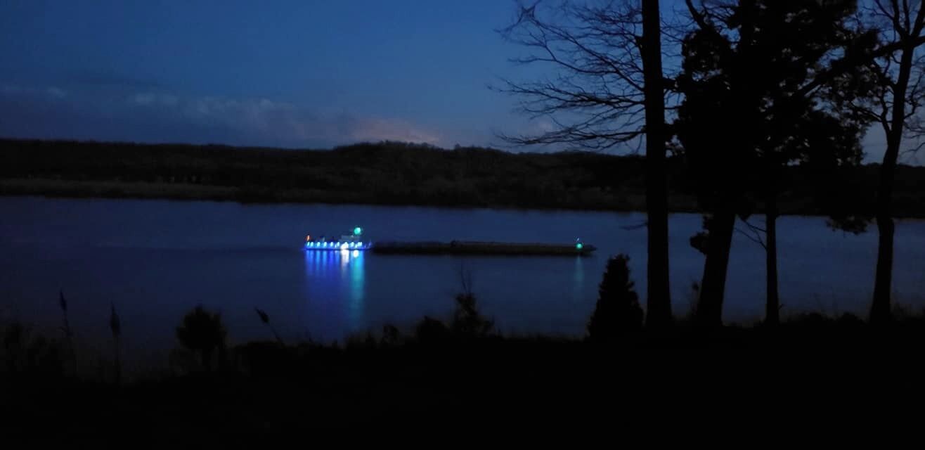 Vista nocturna de un lago con un muelle iluminado.