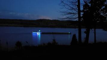 Vista nocturna de un lago con un muelle iluminado.