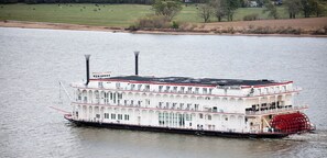 A large white paddle steamer with multiple decks and a prominent red paddle wheel, floating on a calm river. - Deluxe Suite - Bungalow overlooking on the Bluff! (Stone Church Precinct)