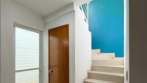 Un intérieur moderne avec une porte en bois, un escalier aux marches beiges et un mur bleu.